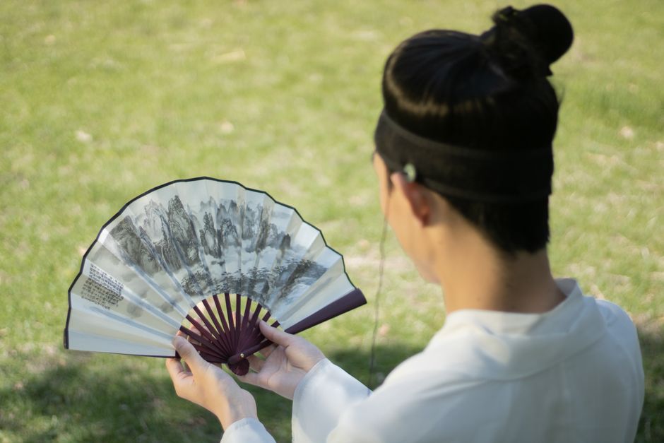 펼친 접부채를 손에 들고 들여다보는 뒷모습